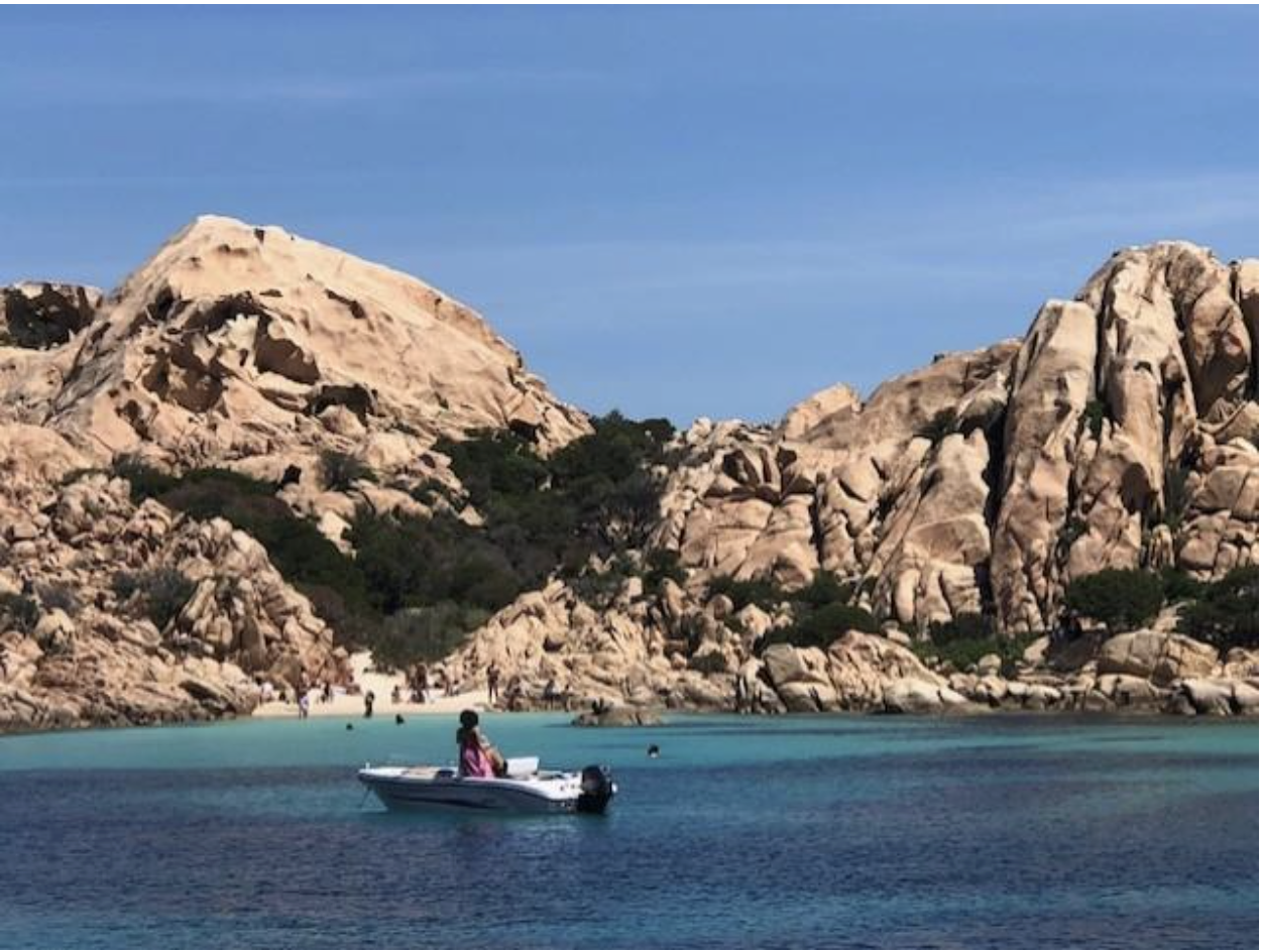 A boat in the water of the stone cliffs of Sardinia 